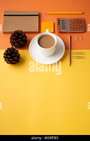 Office or school supplies with coffee cup and pine cones on an orange and yellow background. Flat lay. Back to office or school concept Stock Photo