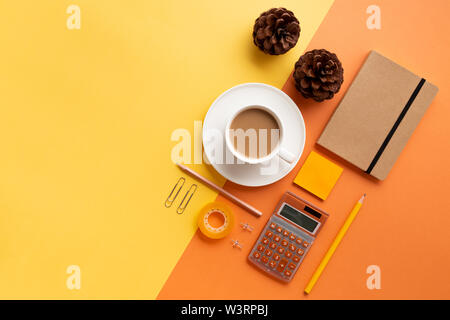 Office or school supplies with coffee cup and pine cones on an orange and yellow background. Flat lay. Back to office or school concept Stock Photo