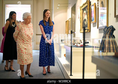 Queen Elizabeth II looks at a dress worn by Albert Edward, Prince of Wales (later King Edward VII) alongside Lucy Peter, assistant curator as part of the exhibition to mark the 200th anniversary of the birth of Queen Victoria for the Summer Opening of Buckingham Palace, London. Stock Photo