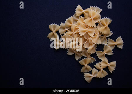 Heap of raw farfalle commonly known as bow tie or butterfly pasta, isolated on black background Stock Photo