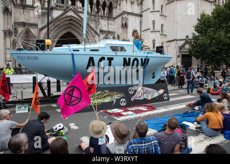 Extinction Rebellion blue boat Polly Higgins during disruption across 5 UK cities calling on Government to ACT NOW outside the Royal Courts of Justice after it was announced last week that more than 1,000 activists who participated in previous demonstrations were facing prosecution, on 15th July 2019 in London, England, United Kingdom. Extinction Rebellion is a climate change group started in 2018 and has gained a huge following of people committed to peaceful protests. These protests are highlighting that the government is not doing enough to avoid catastrophic climate change and to demand th Stock Photo