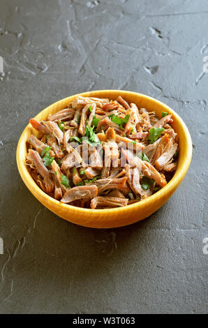 Slow cooked pulled pork for sandwiches with parsley in wooden bowl Stock Photo