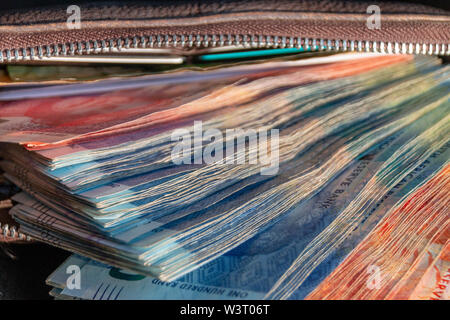 A close up view of pile of two hundred, one hundred and fifty rand sound african notes coming out the front of a brown leather wallet Stock Photo