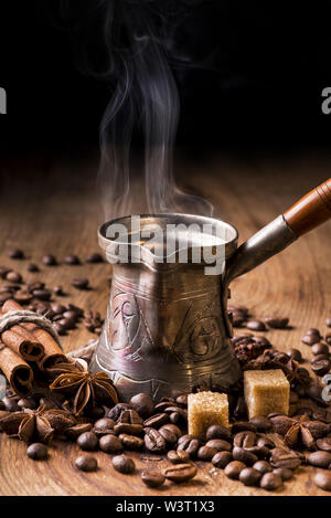 turkish coffee boiling in coffee pot and roasted coffee beans on wooden table Stock Photo