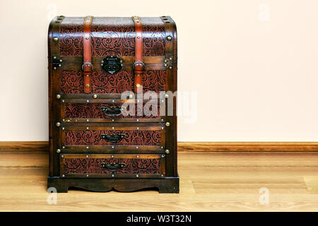 Commode, made in the form of an old chest of brown against a pink wall. Stock Photo