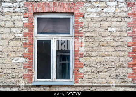 Rectangular window with a white wooden frame on the background of the old wall of stone and brick. From the window series of the world. Stock Photo