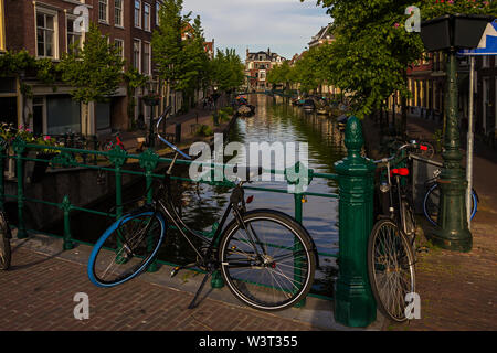 Leiden, Holland, Netherlands, April 18, 2019, bicycles parked on a bridge and along a street, canal in Leiden old town. Flowers in a flowerbeds, boats Stock Photo