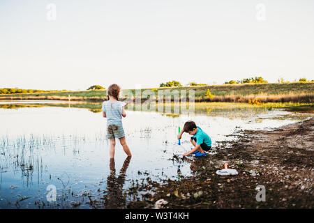 Young girl and boy catching fish with a fishing pole and net at lake Stock Photo