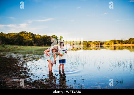 Young girl and boy looking at fish they caught in a net at the lake Stock Photo