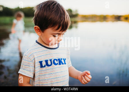 Close up of young boy standing in water at the lake in summer