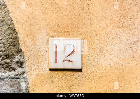 house number twelve ( 12 ) on a roughcast wall Stock Photo