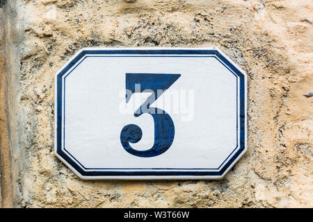 house number three ( 3 ) on a roughcast wall Stock Photo