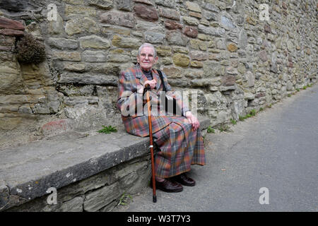 Elderly lady sitting on stone seat taking a well earned rest on the steep climb into Ludlow Stock Photo