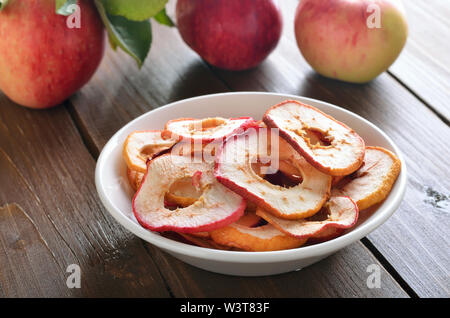 Dried apple rings in white bowl on a wooden table, close up view Stock Photo
