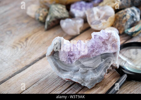 Mineral stones collection. Amethyst with agate and magnifying glass in the foreground. Stock Photo