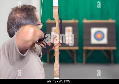 Senior Archer Training With The Bow. Shooting the target in the background . Stock Photo