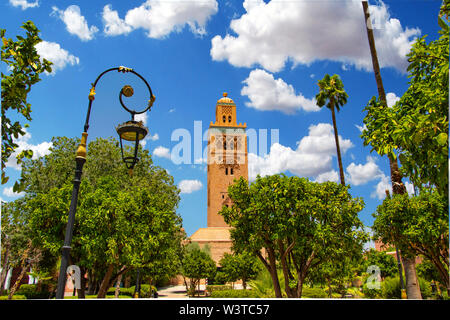 Koutoubia Mosque minaret at medina quarter of Marrakesh, Morocco. There is beautiful green garden with palms. Blue sky is in the background. Stock Photo