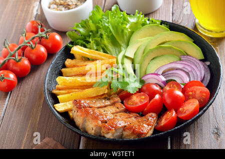 Roasted sliced pork steak with vegetables in frying pan, close up view Stock Photo