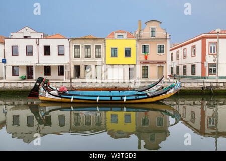 Colorful moliceiro boat and city architecture reflected in calm Cojo canal waters, early morning in Aveiro, Portugal. Stock Photo