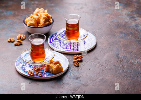 Traditional Turkish black tea in glass at decorative plates on concrete background Stock Photo
