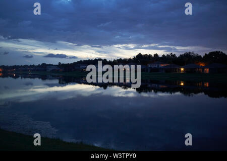 sun settting over houses in a gated community surrounding a lake in kissimmee florida USA United States of America Stock Photo