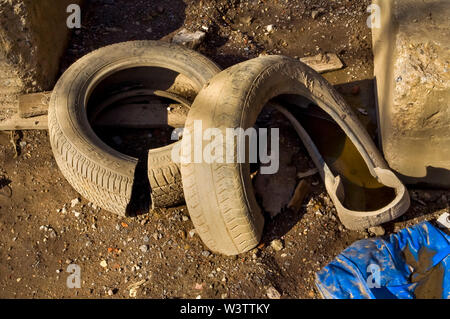 Two car tyres dumped on waste ground in bright sunshine Stock Photo