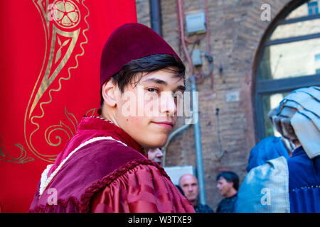 A young dressed in medieval garb and costume smiles before the beginning of the Palio parade in Siena, Italy Stock Photo