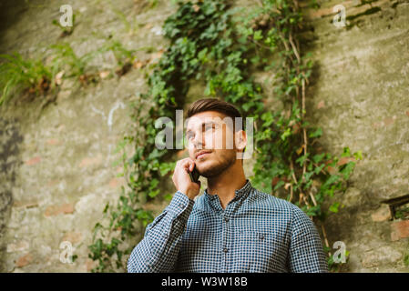 Young man sitting in a cafe, drinking coffee and talking on a mobile phone Stock Photo