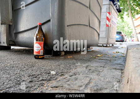 A one litre bottle of Alhmabra tradicional beer abandoned by the side of the street near a trash bin and sidewalk in Granada, Spain. Stock Photo