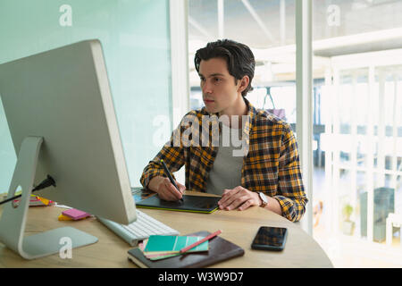 Male graphic designer using graphic tablet at desk Stock Photo