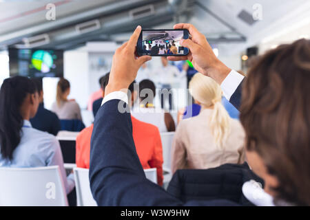 Close-up of Businessman clicking photo of business seminar with mobile phone Stock Photo