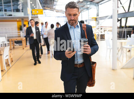 Businessman using mobile phone while walking in the corridor Stock Photo