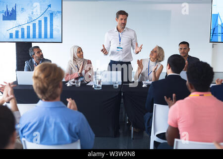 Business people applauding male speaker in business seminar Stock Photo