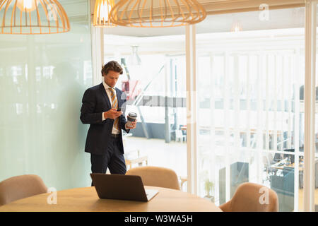 Businessman using mobile phone while having coffee in the conference room Stock Photo