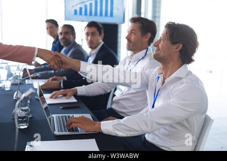 Business people shaking hands with each other while checking in business seminar Stock Photo