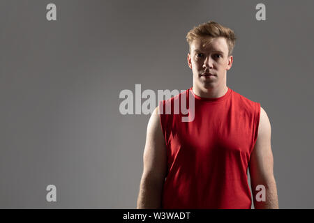 American football player standing against grey background Stock Photo