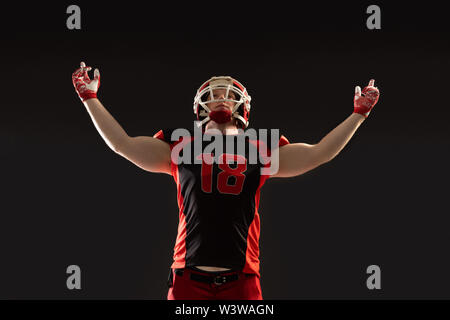 American football player standing against black background Stock Photo