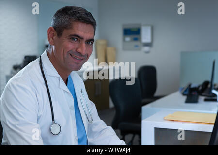 Male doctor in lab coat looking at camera in hospital Stock Photo