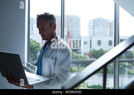 Male doctor using laptop while walking on stairs Stock Photo