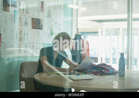 Female fashion designer working at desk in design studio Stock Photo