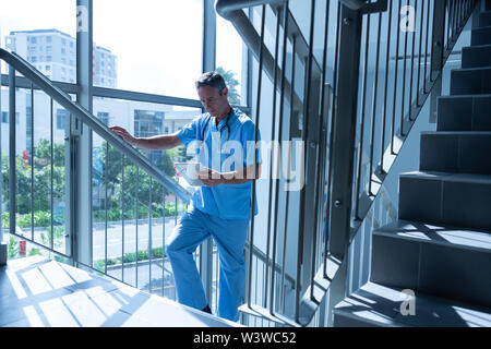 Male doctor using digital tablet while going upstairs Stock Photo
