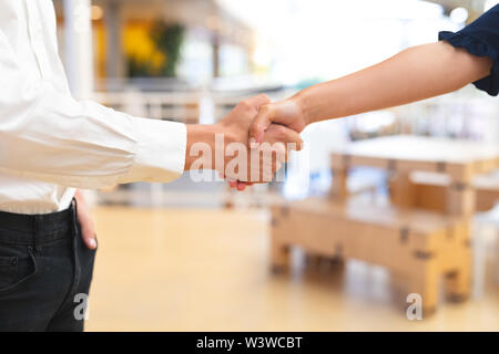Business people shaking hands with each other in corridor at office Stock Photo