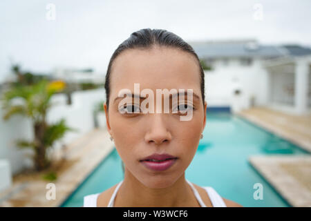 Fit woman standing near swimming pool in the backyard Stock Photo