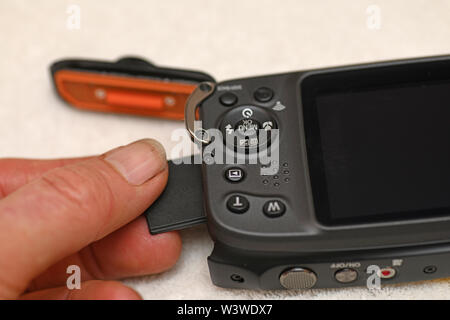 A person inserts a memory stick into a new waterproof camera Stock Photo