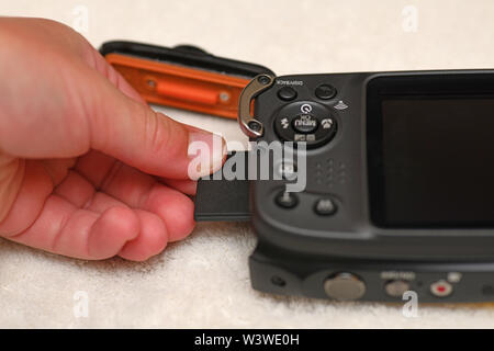 A person inserts a memory stick into a new waterproof camera Stock Photo