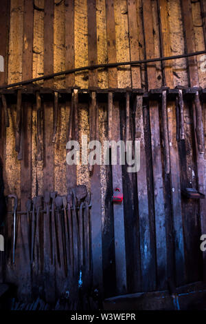 blacksmith tools hanging on a wooden wall Stock Photo
