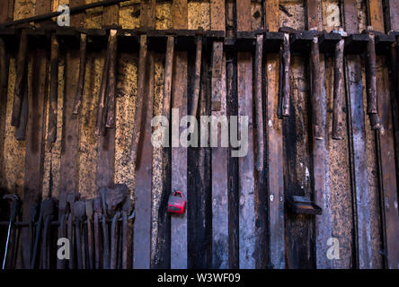 blacksmith tools hanging on a wooden wall Stock Photo
