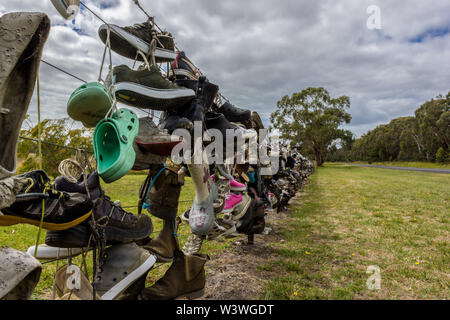 Old shoes on a fence next to a road in Australia. tourist put their old shoes on the fence. Stock Photo