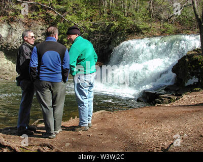 Middletown, CT USA. Mar 2015. Elderly men talking outdoors by a small and quite loud waterfall. Stock Photo
