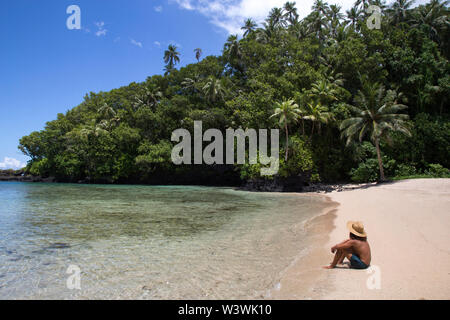 tanned man, sitted on sandy tropical beach, during sunny summer day Stock Photo